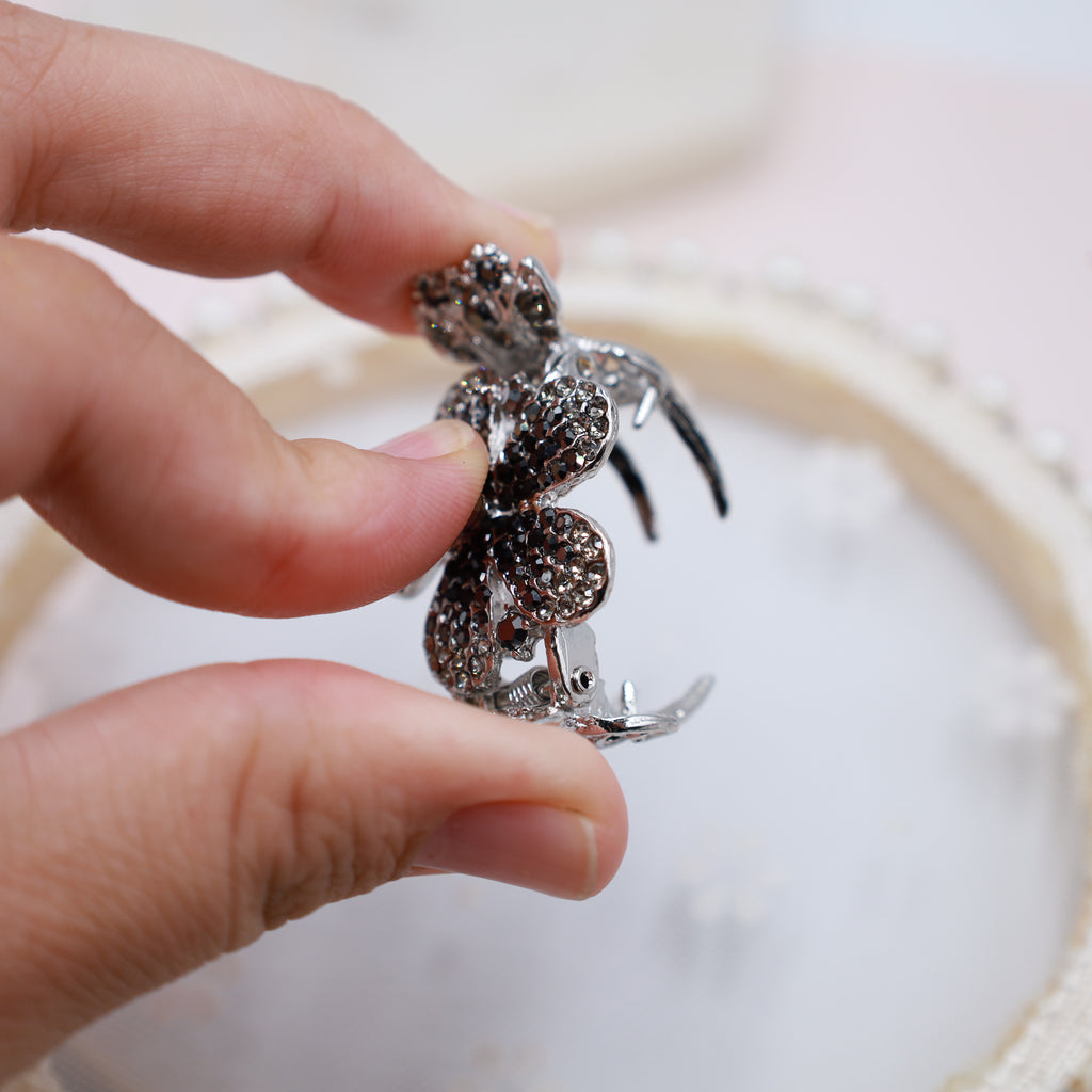 Close-up of a black rhinestone hair claw with intricate detailing.