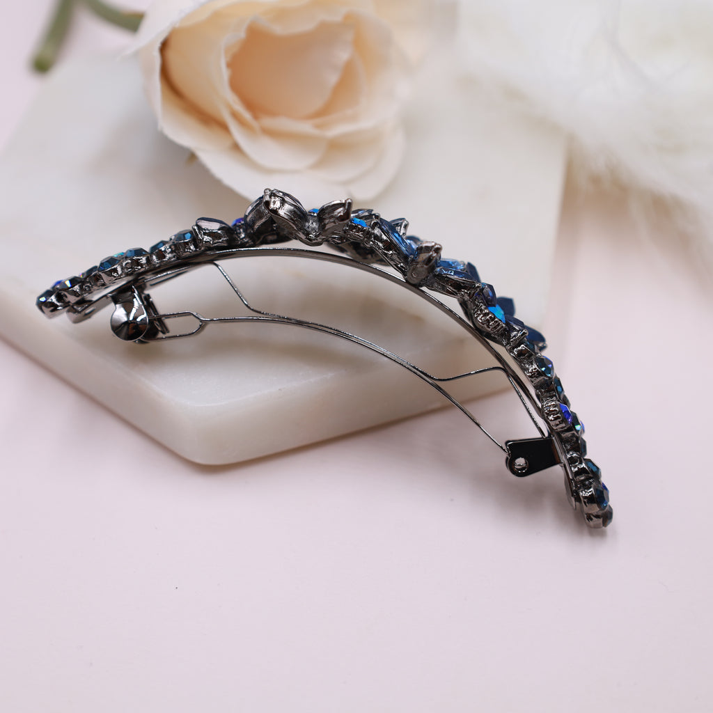 Close-up of navy blue rhinestone flower hair barrette held by hand, highlighting the sparkling crystal details.